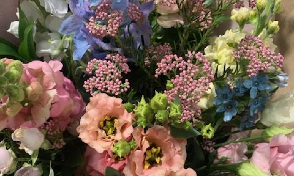 Hand-tied bouquet with lisianthus and spray roses by H Watts Florist